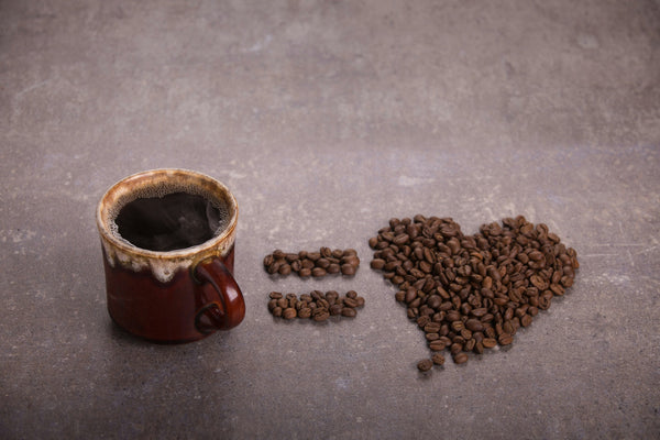 Coffee beans beside a ceramic cup