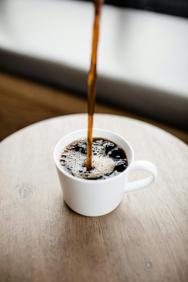 Black coffee being poured into a white ceramic cup