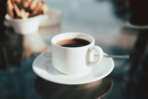 A cup of black coffee on a white saucer