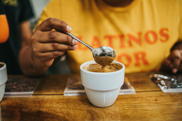 Person holding a silver cupping spoon over a white ceramic bowl