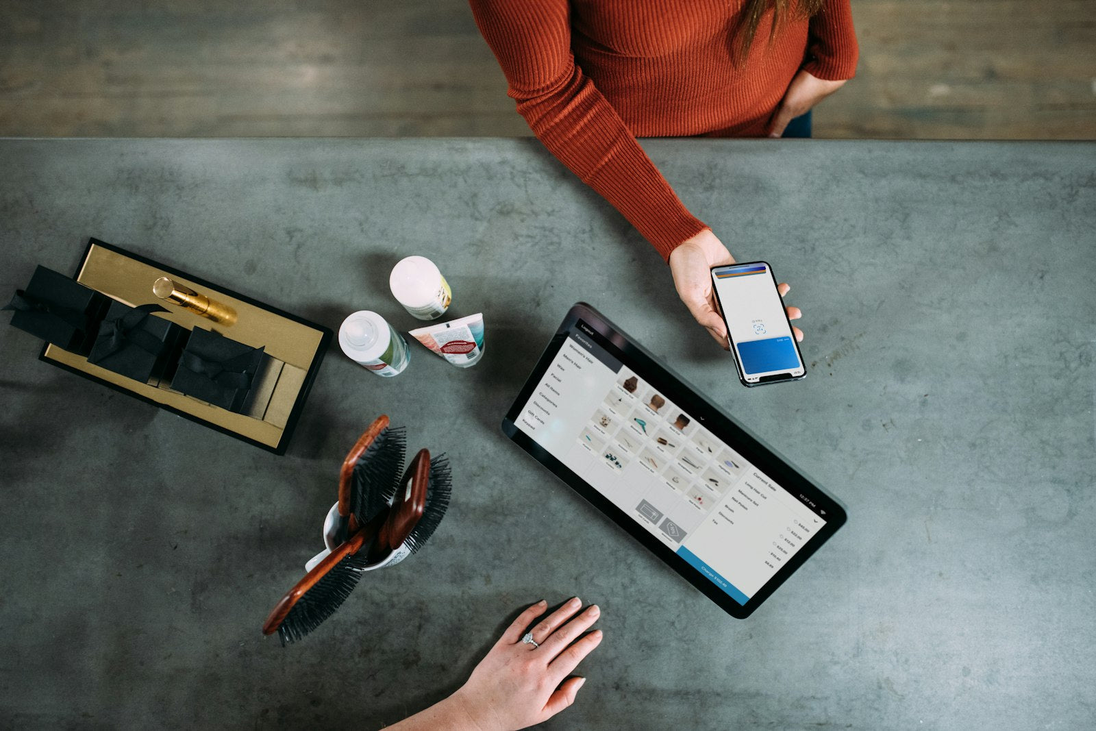 Person holding a smartphone beside a tablet computer, making a payment