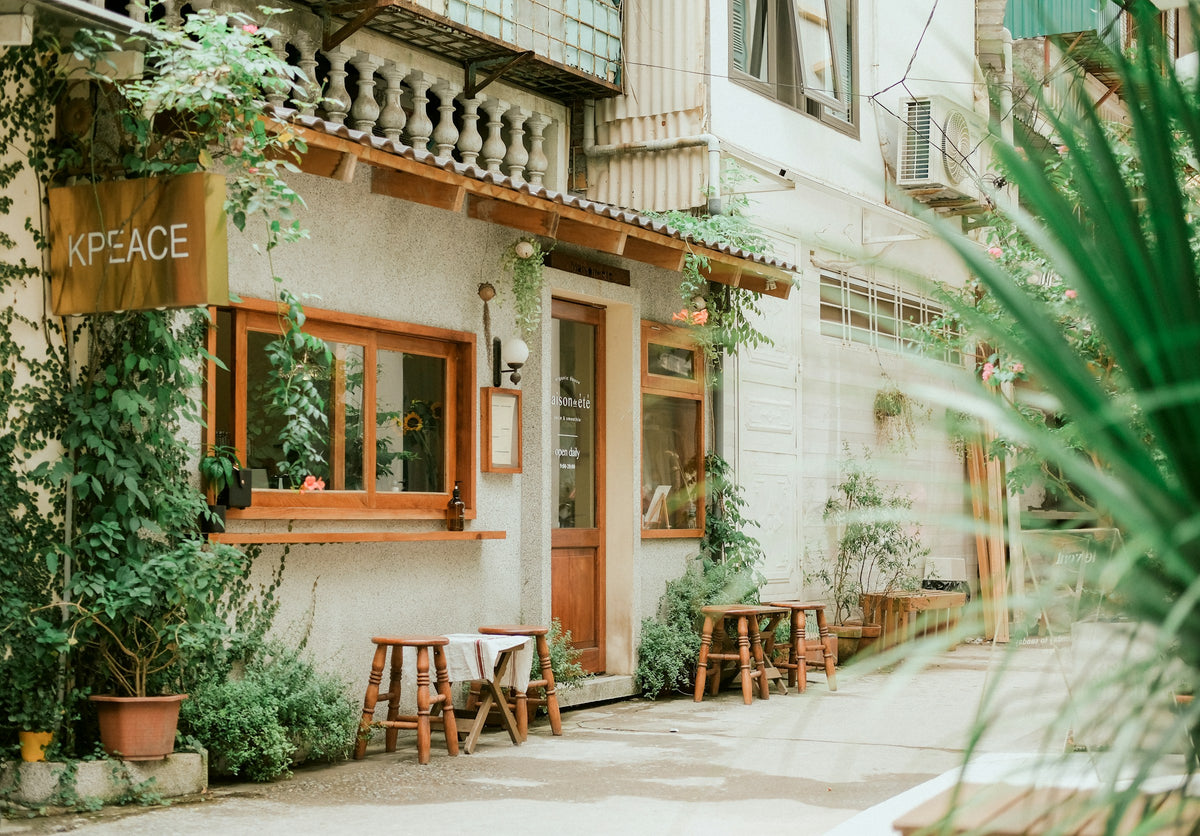 Small coffee shop front with wooden windows, vines and stools, Vietnam