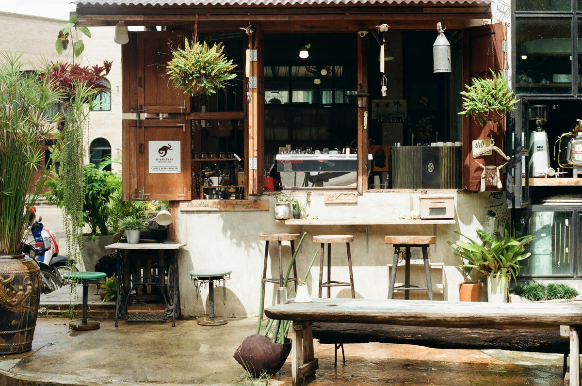 Open-air coffee bar with an espresso machine, plants and wooden seating, Thailand